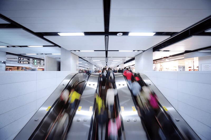 People heading down escalator