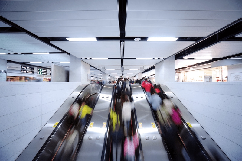 People heading down escalator